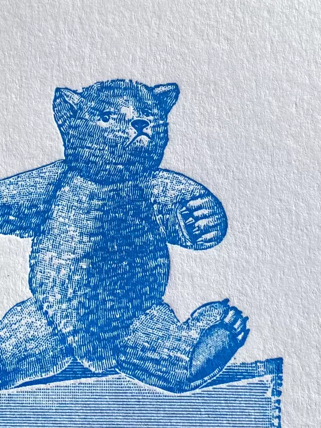 Close up of a white card with a blue illustration of a teddy bear