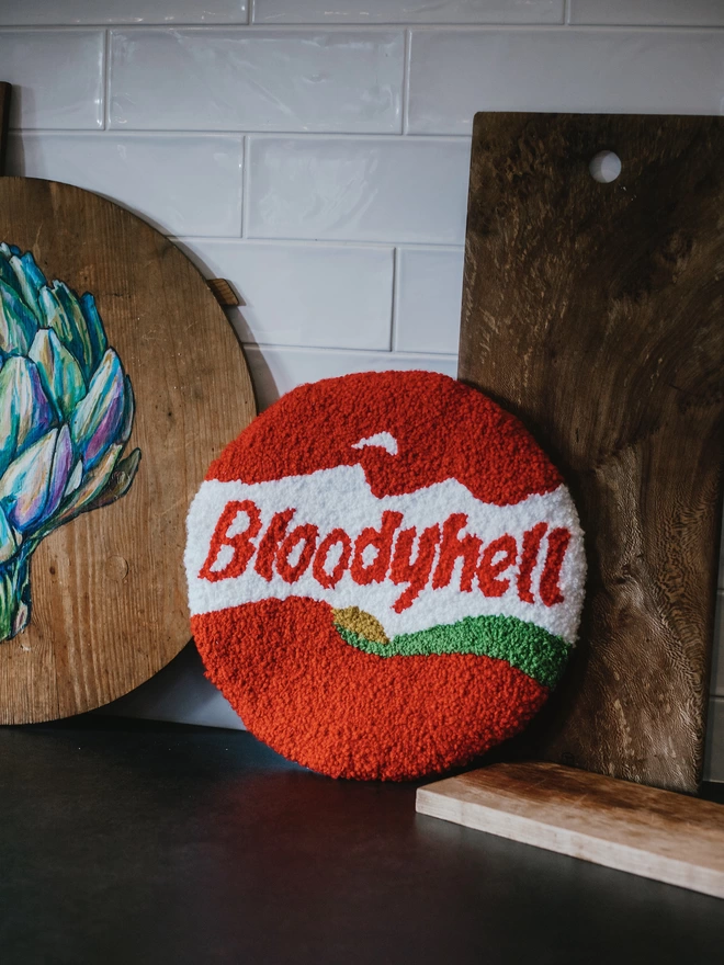 'Bloody Hell' Handmade Tufted Rug/Wall Hanging seen in a kitchen with wooden chopping boards behind.