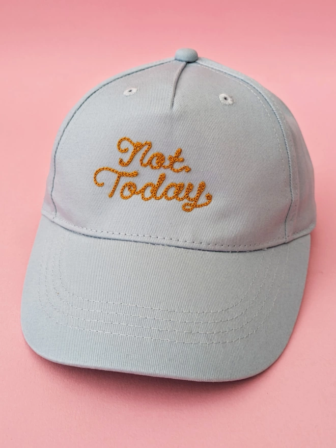 Powder blue kids baseball hat, featuring Gold Embroidery reading "Not Today" in cursive lettering, on a pink background