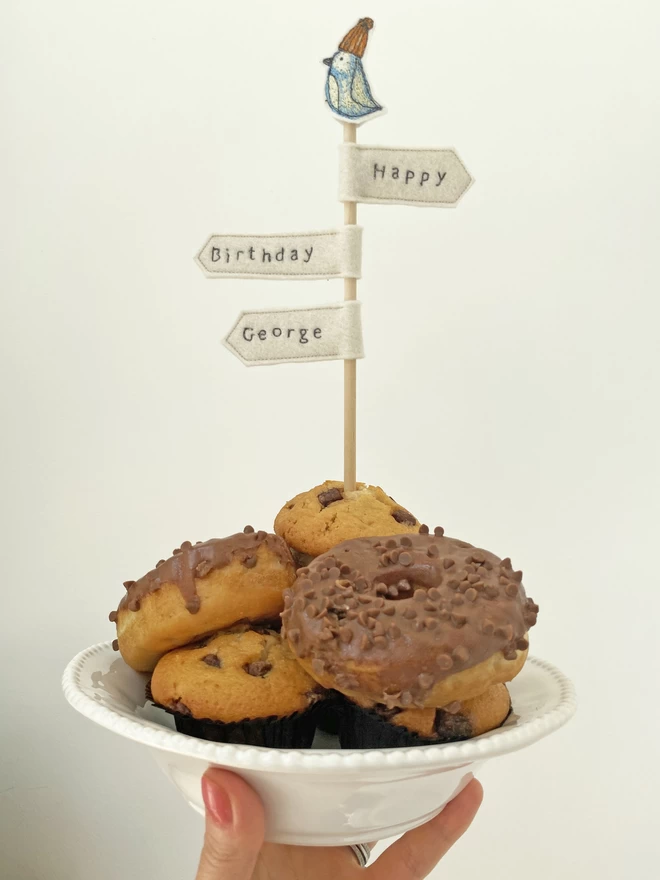 Signpost Cake Topper in a bowl of cakes being held