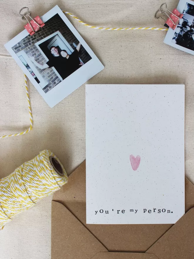 'You're My Person' Card laying on surface with yellow and whit twine and polaroid pictures of couple