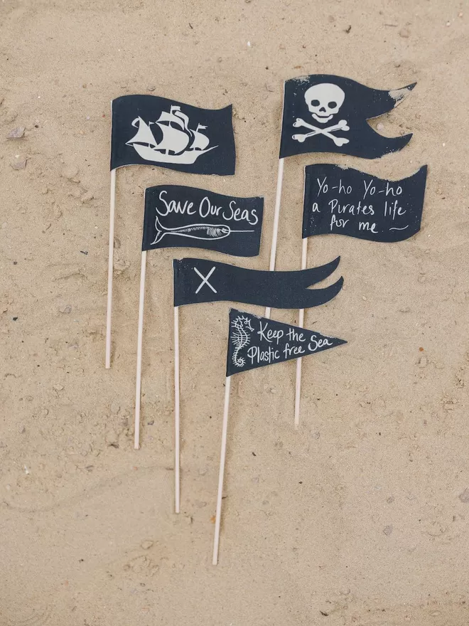 Pirate flags laid out on the beach for a sandcastle by Caro B.