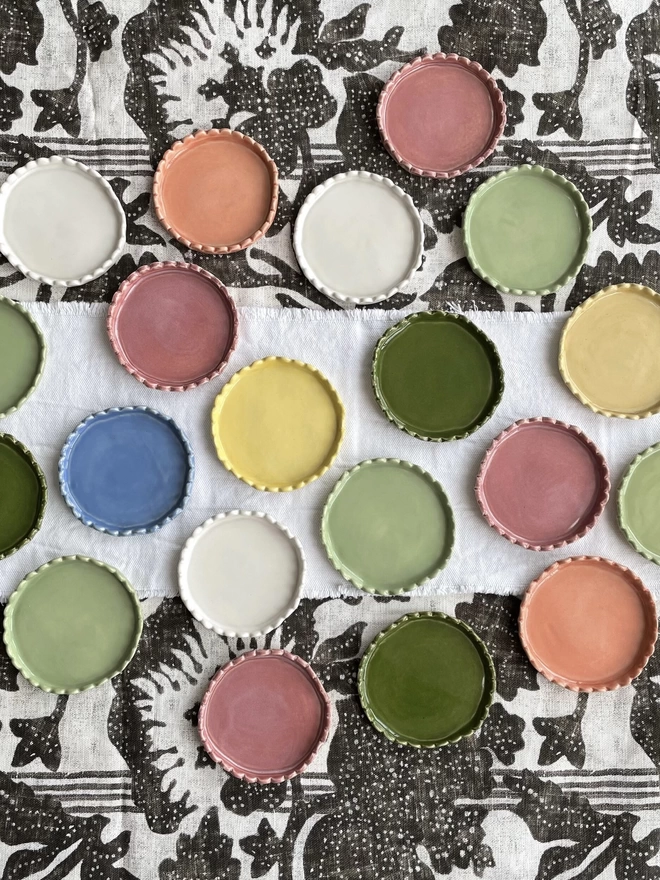 a tabletop covered in scalloped edge coasters of different colours
