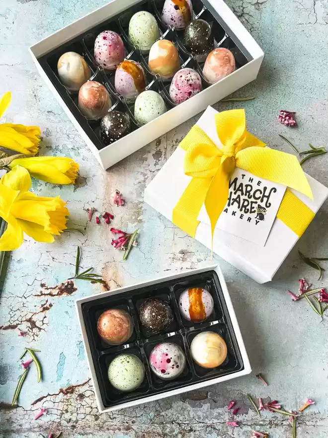 an assortment of chocolates in a white box with a yellow ribbon.
