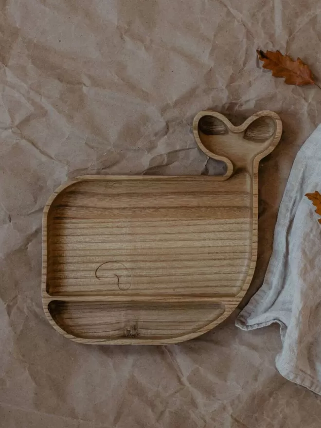 Wooden whale plate empty in a birdseye view on a brown paper tablecloth