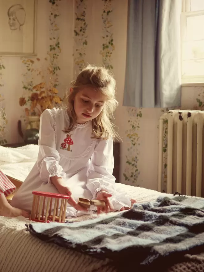 A girl on a bed plays with toys