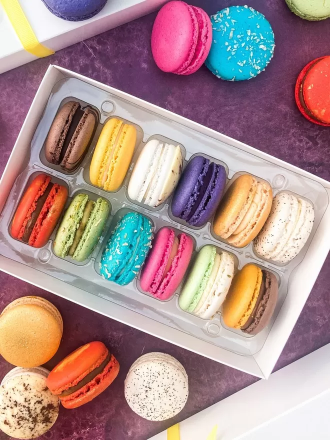 colourful macarons in a white gift box on a purple background
