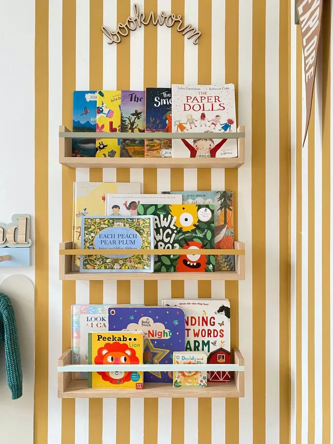 A fun stripy yellow kids room. Three beautiful Autumn's Corner wood bookshelves in a row, filled with children's books.