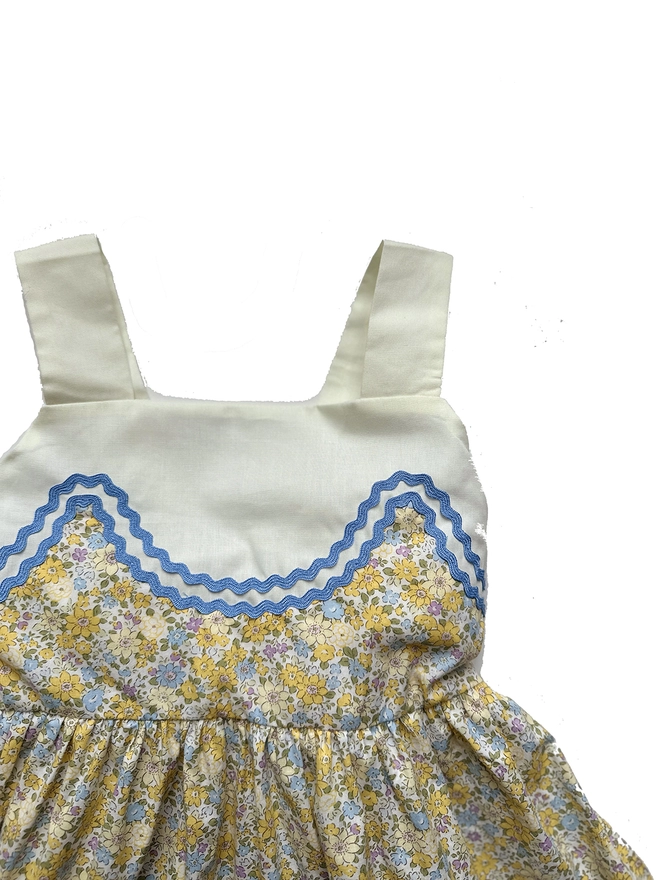 Detail of yellow floral sundress with upper and straps in pale lemon and blue rikrak detail.