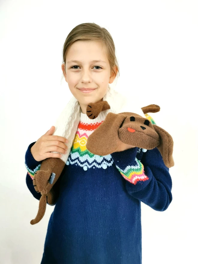 A smiling girl holds Dolly the Dachshund long hot water bottle around her neck.