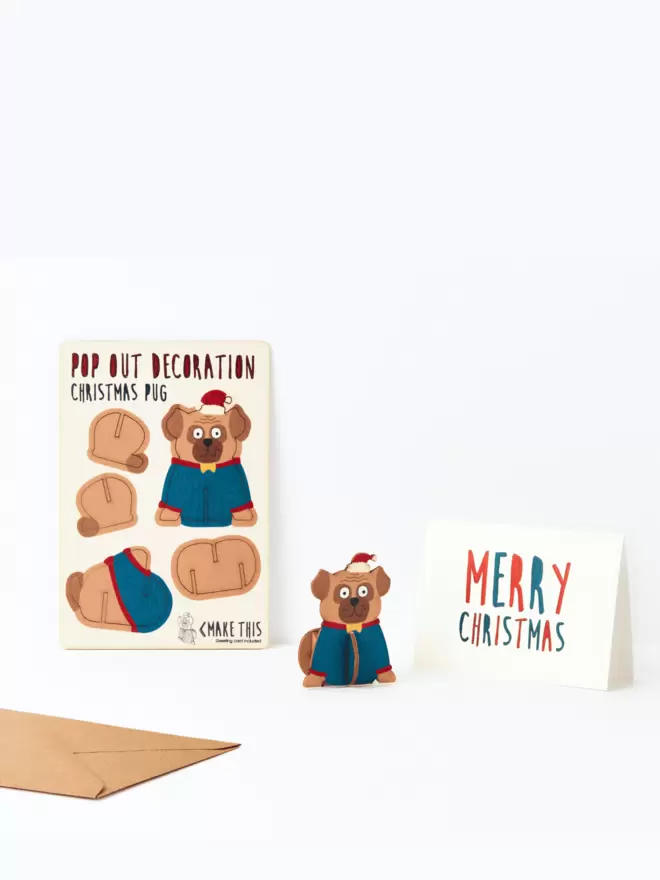 Pop out Pug Christmas decoration and Merry Christmas card and brown kraft envelope on a white background