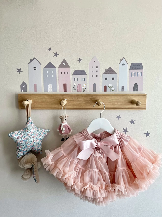 Girls bedroom with wall hooks, pink tutu and little village house stickers