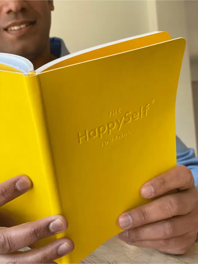 Man holding a Grown-Up edition of the HappySelf Journal