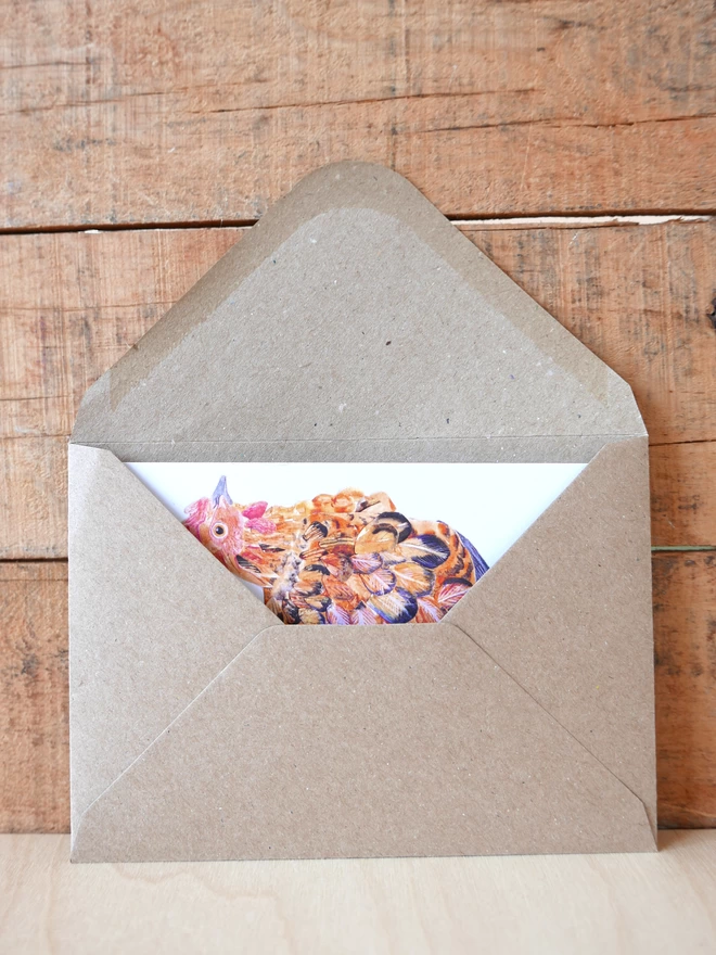 The Mother Hen Card tucked inside its brown envelope with some of the design visible