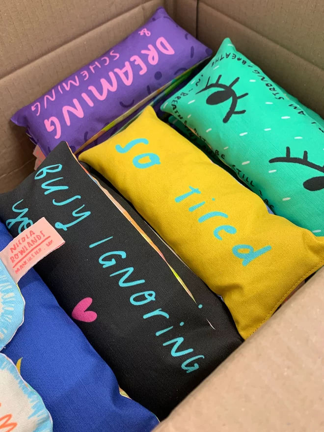 A box full of different designs of lavender eye pillows by Nicola Rowlands in bright colourful designs. 