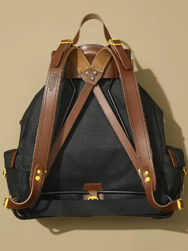 Back view of the Black Marten Rockness backpack showing black frame, brown leather and yellow hardware.