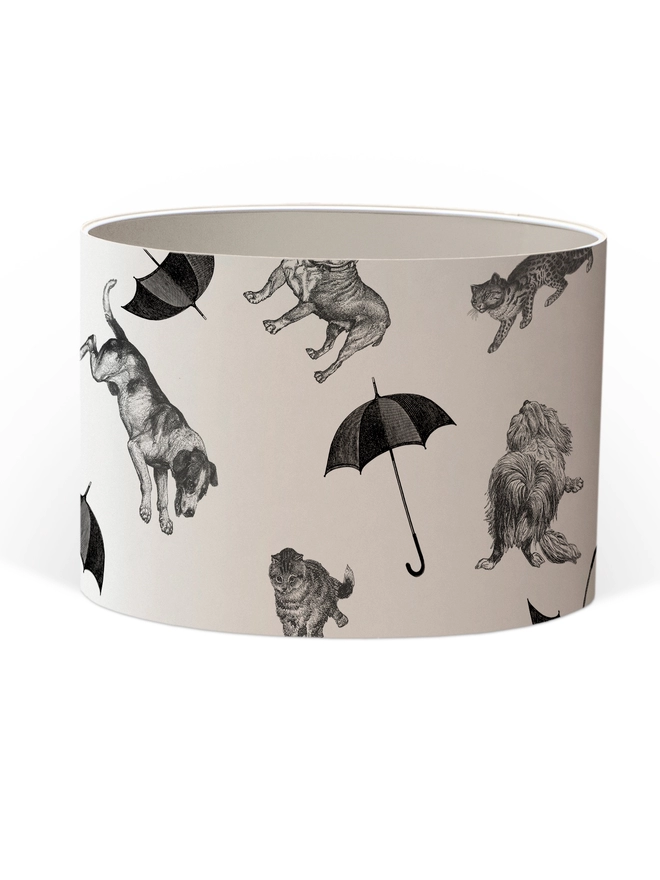 Drum Lampshade featuring cats and dogs ‘raining’ from the sky with a white inner on a white background