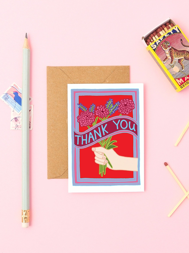 A thank you card with a bunch of flowers. Held by a white hand