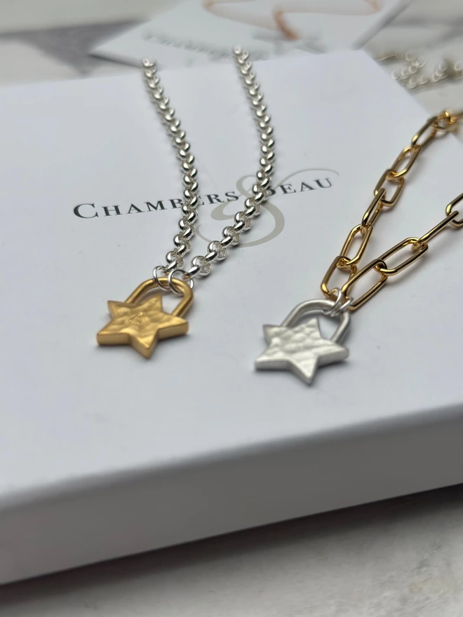 sterling silver chain with a gold star padlock charm, layered with a gold shooting star necklace on silver chain with a silver star padlock charm on a gold mini paperclip chain