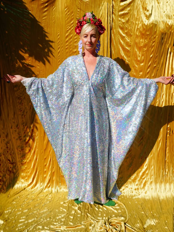 Silver Holographic Sequin V-neck Kaftan GownSilver Holographic Sequin V-neck Kaftan Gown seen from the front with her arms up.