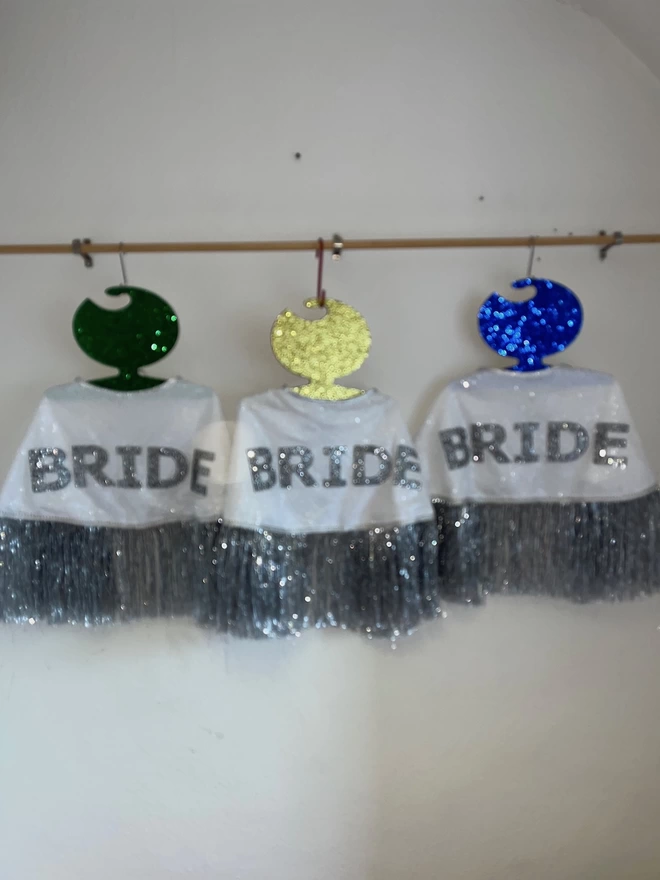 Three gretna bride capes hanging on a rail. 