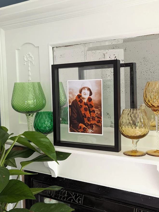 Print of woman wearing embroidered leopard print trim coat framed on shelf