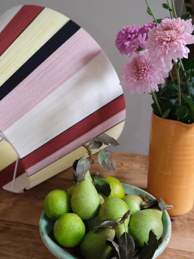 Lifestyle image of New Neutrals lampshade a table with fruit and flowers.