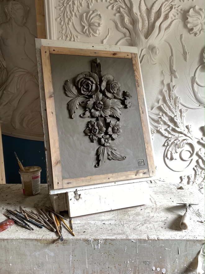 Clay modello of flower sculpture on easel with modelling tools