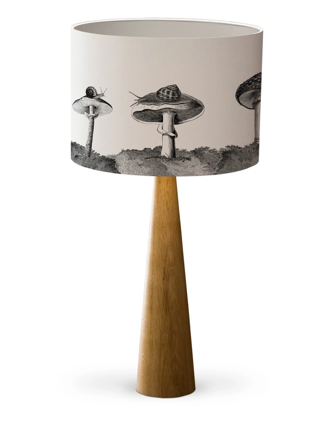Drum Lampshade featuring snails sitting on mushrooms and toadstools with a white inner on a wooden base 