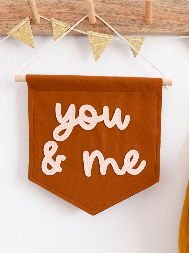 felt banner with the words you and me sewn on in cursive text.