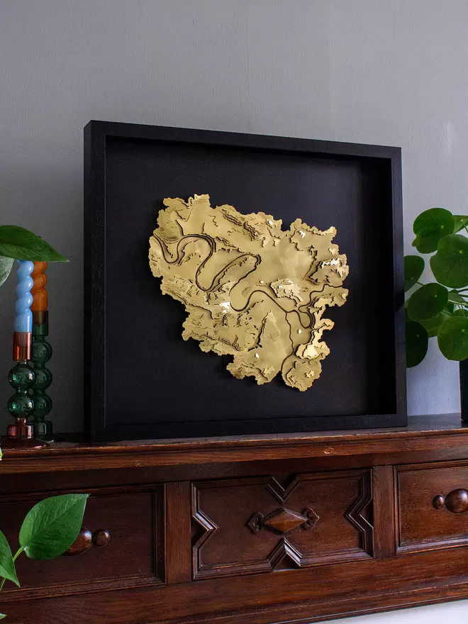 Side view of the gold finish Paris contour map wall piece framed in black with a black background