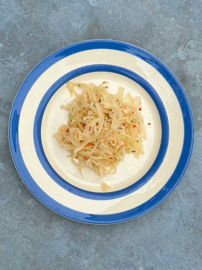 Muti Chilli Kraut On A Blue And White Plate Atop A Steel Topped Table.