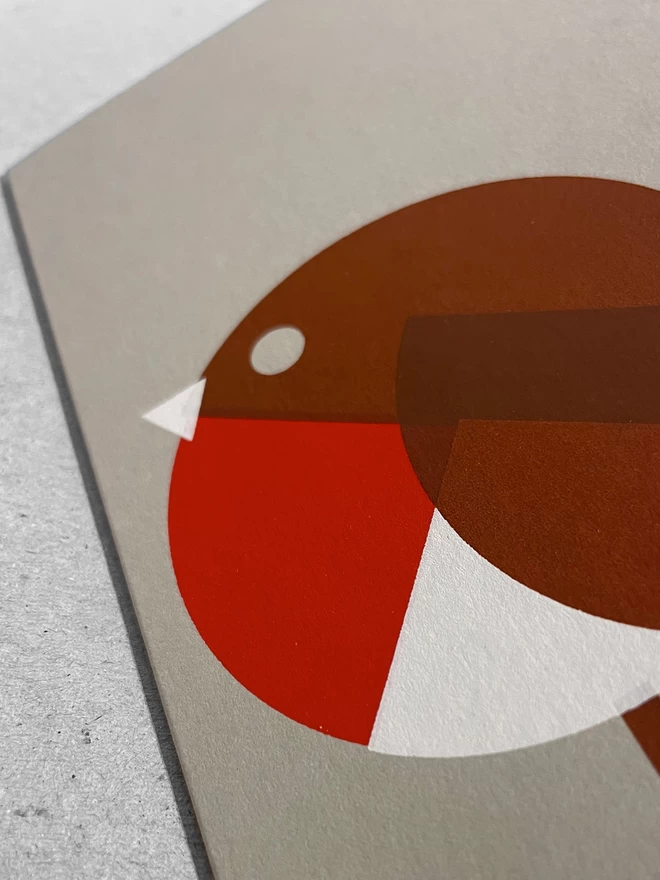 Close up of a handprinted robin christmas card. Geometric shapes in red white and brown make up this cool screenprinted robin design.
