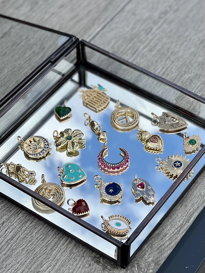 Collection of colourful gold lucky charms inside a mirrored jewellery box with the reflection of a blue sky