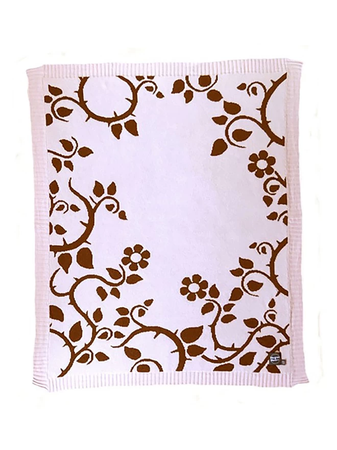 Product shot of the front of the blush briar rose junior blanket, blush pink baclground with choco;te brown trailing thorn and flower design.