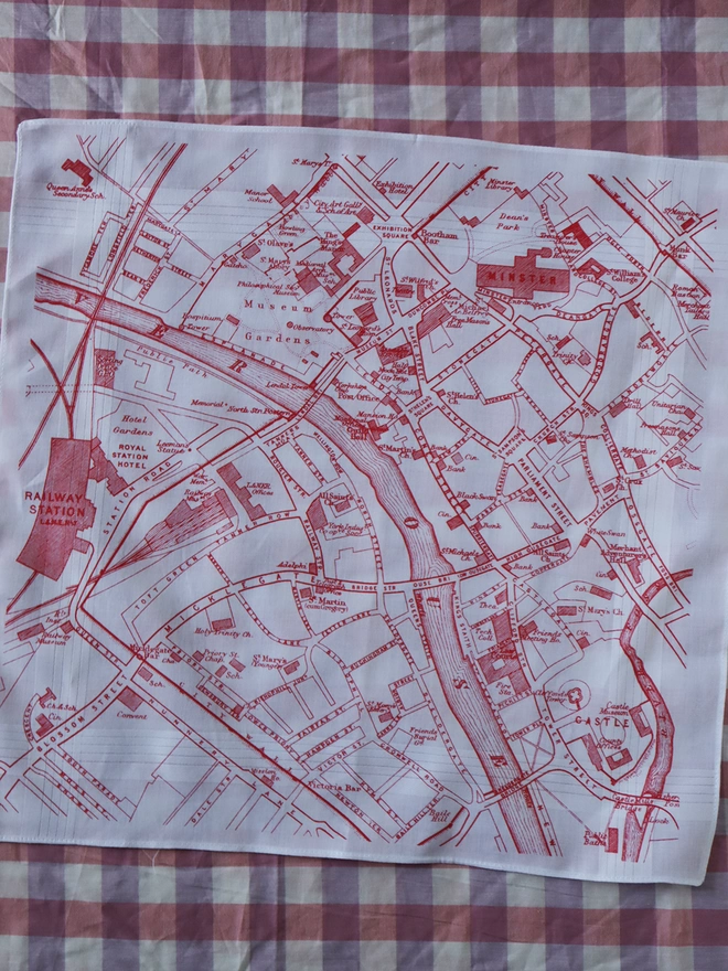 A Mr.PS York map hankie printed in red laid flat on a gingham tablecloth