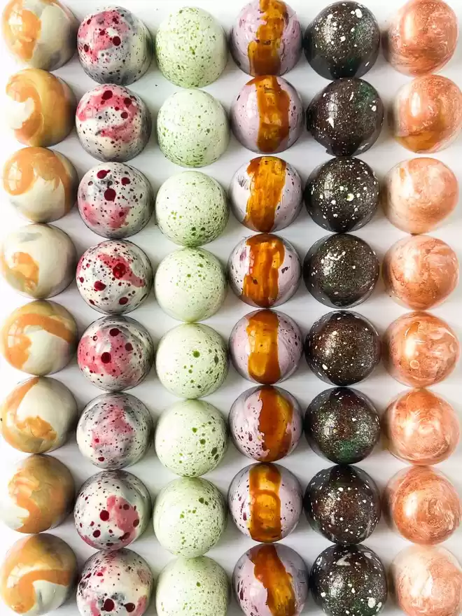 an assortment of chocolates arranged in a square on a white surface
