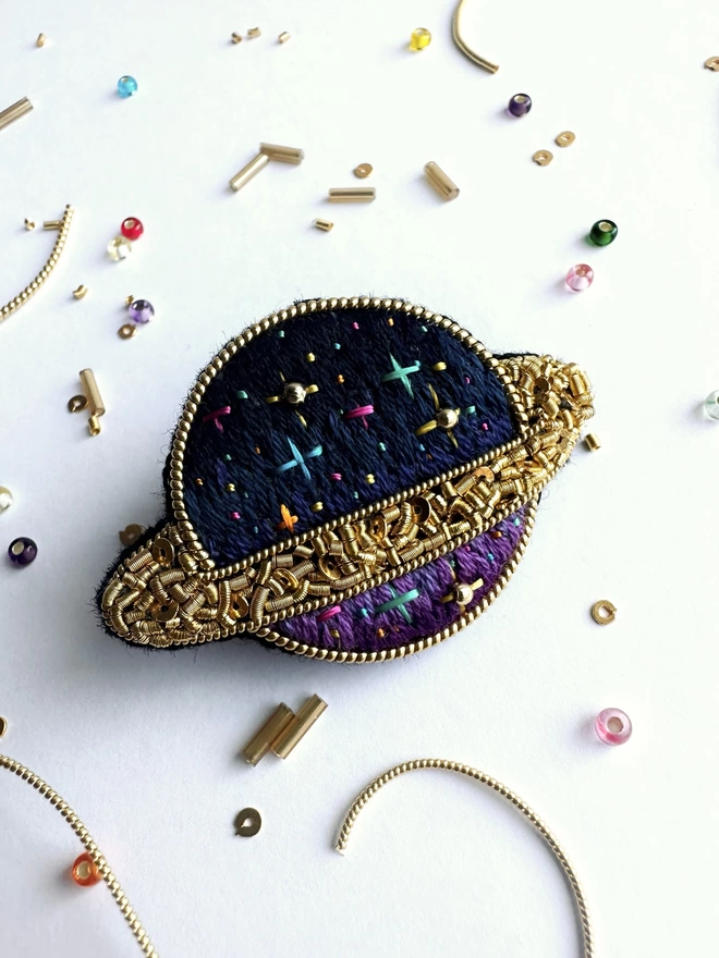 Planet brooch on background with beads