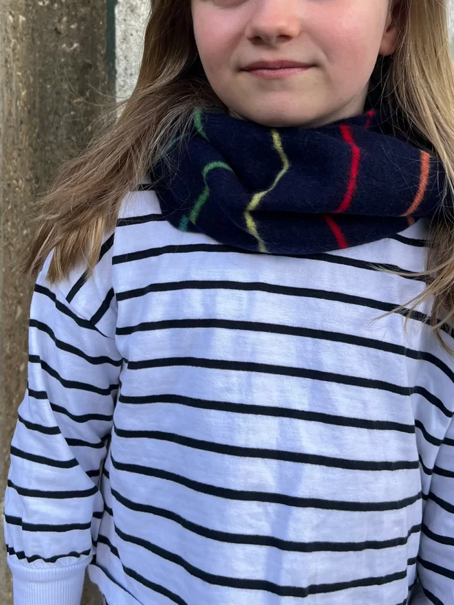 Navy knitted snood with colourful thin stripes being worn by child