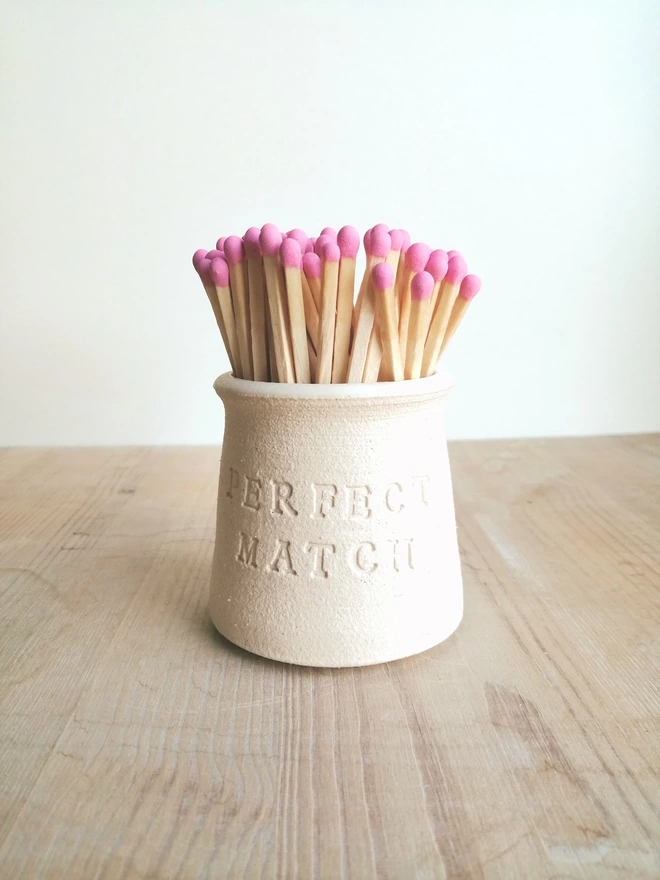 White match pot with perfect match on the front, pink coloured matches inside pot