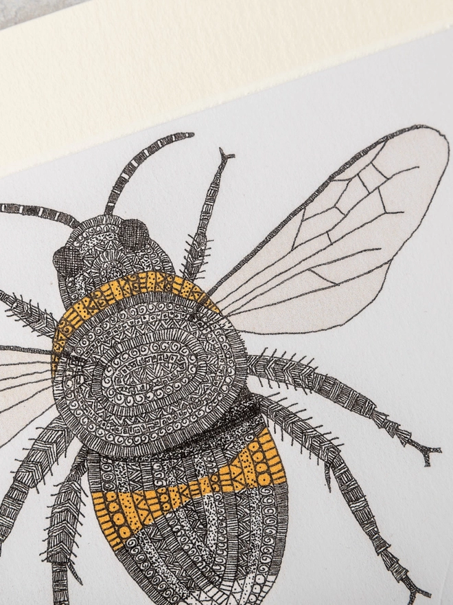 Note card with intricately patterned pen and watercolour drawing of a bee, in a soft white mount