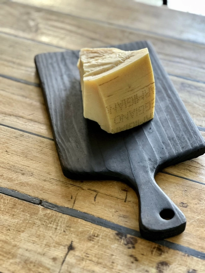 Round Handle Charred Black Serving Board With Cheese on it
