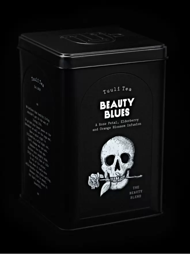 A black tin of Beauty Blues herbal tea photographed on a black background. 