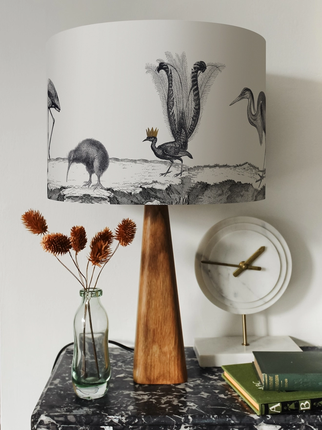 Drum Lampshade featuring birds on a wooden base on a shelf with books and ornaments