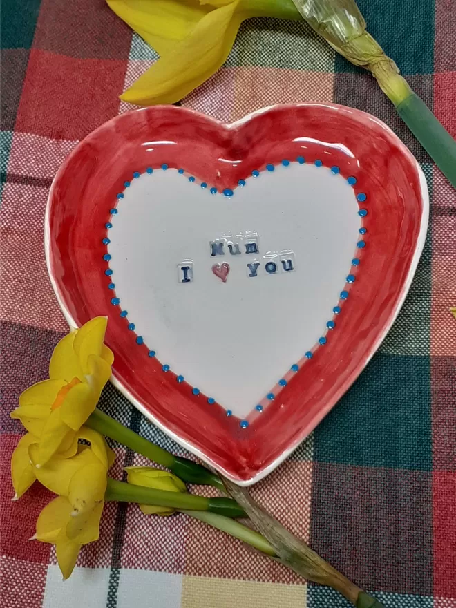 Heart shaped ceramic dish with the words Mum I (heart symbol) You. decorated with a red border with blue dots. Perfect for a Mother's Day Gift