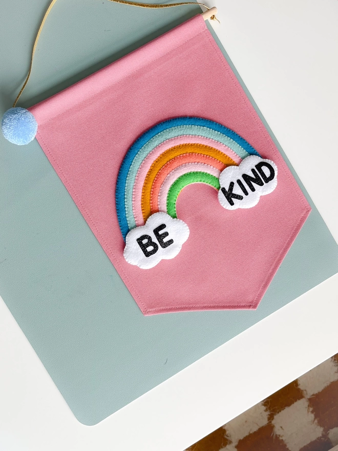Pink be kind rainbow banner on a table