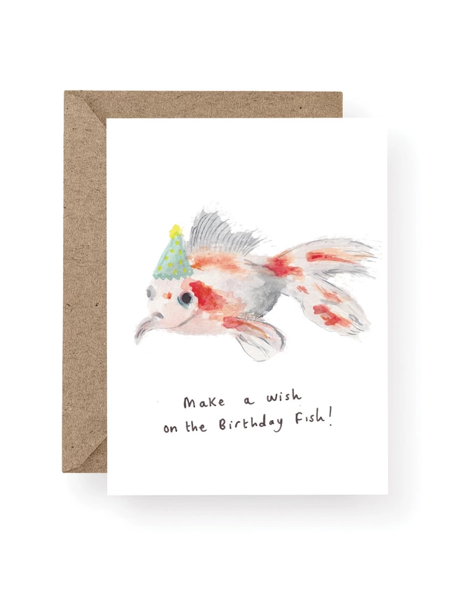  Goldfish Birthday Card, Card Has a White Base With Hand Painted Goldfish Wearing A Party Hat.  Sitting On A Recycled Brown Kraft Envelope.  There Is Black Handwritten Text Underneath The Goldfish Which Reads ‘ Make a Wish On the Birthday Fish’