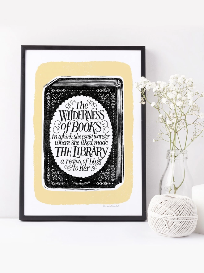black and yellow book quote print in black frame with white flowers