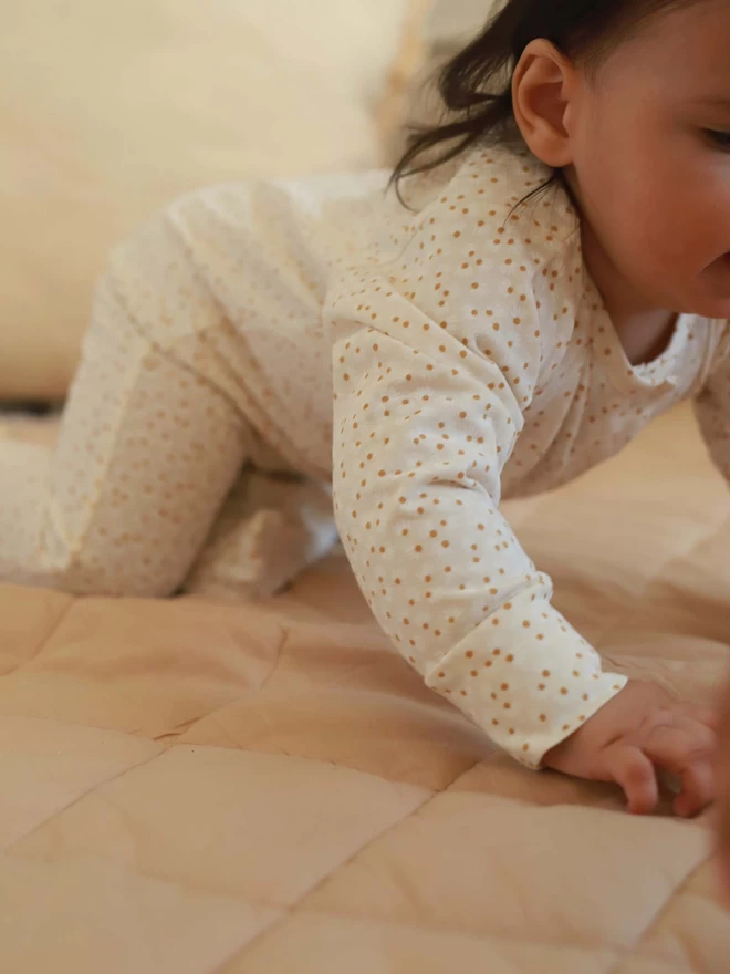 A printed sleepsuit worn by baby trying to crawl for the first time