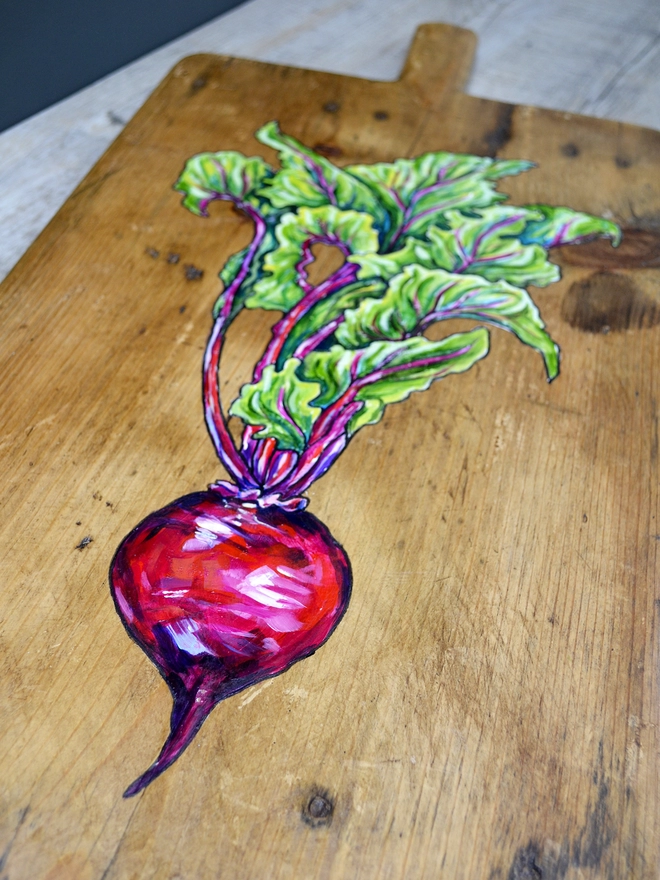 Close up of a wooden chopping board with handpainted design of a beetroot